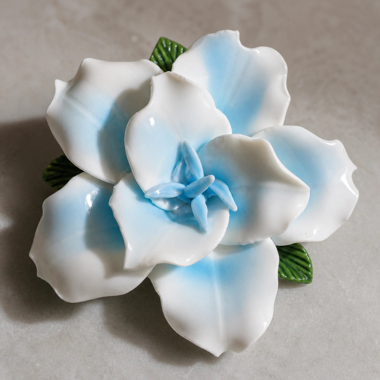 Close view of powder blue glaze, broad white petals and the pointed center of a ceramic lily magnet.