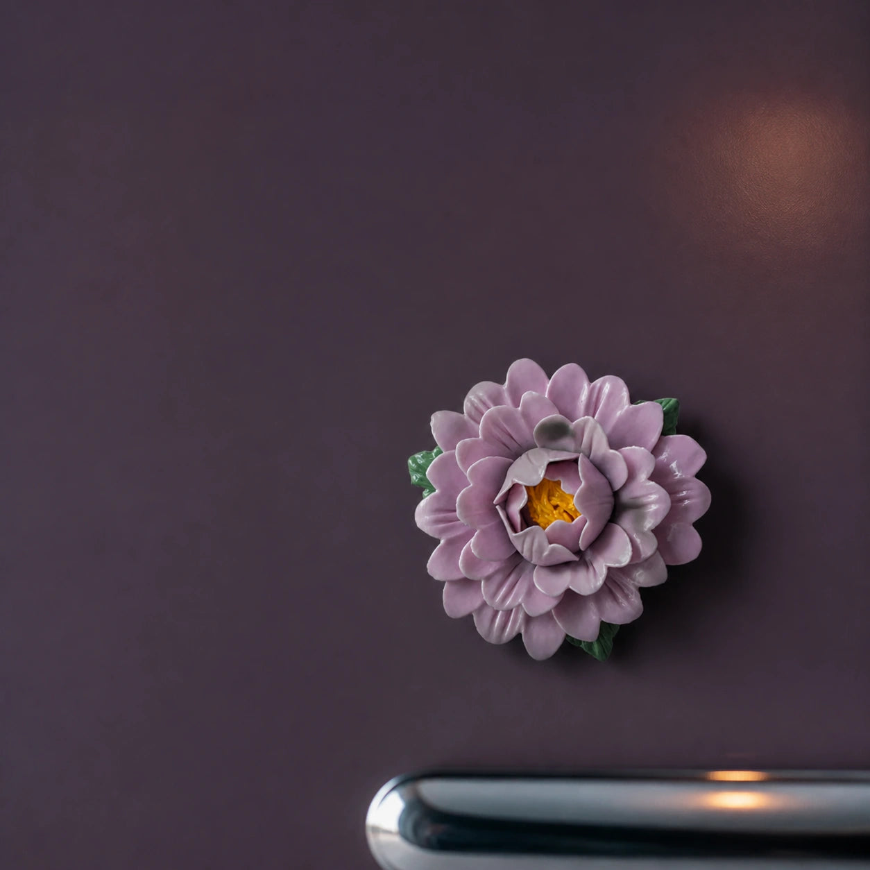 Aimant pivoine en céramique lavande sur un réfrigérateur aubergine à l’heure bleue.
