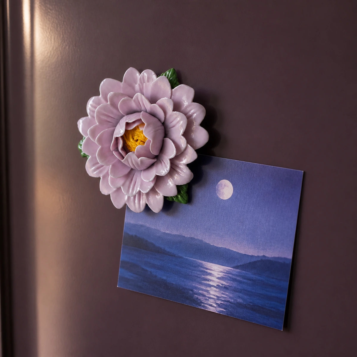 Aimant pivoine en céramique lavande retenant une carte de paysage indigo au clair de lune.