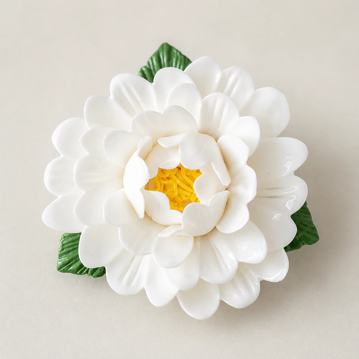 Aimant pivoine en céramique blanc chaud sur fond neutre clair.