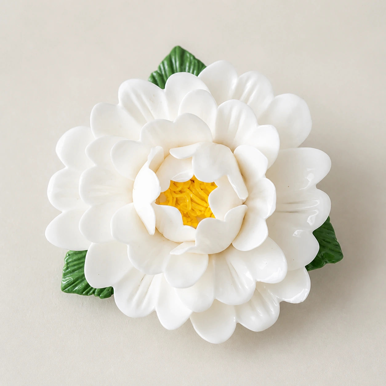Aimant pivoine en céramique blanc chaud sur fond neutre clair.