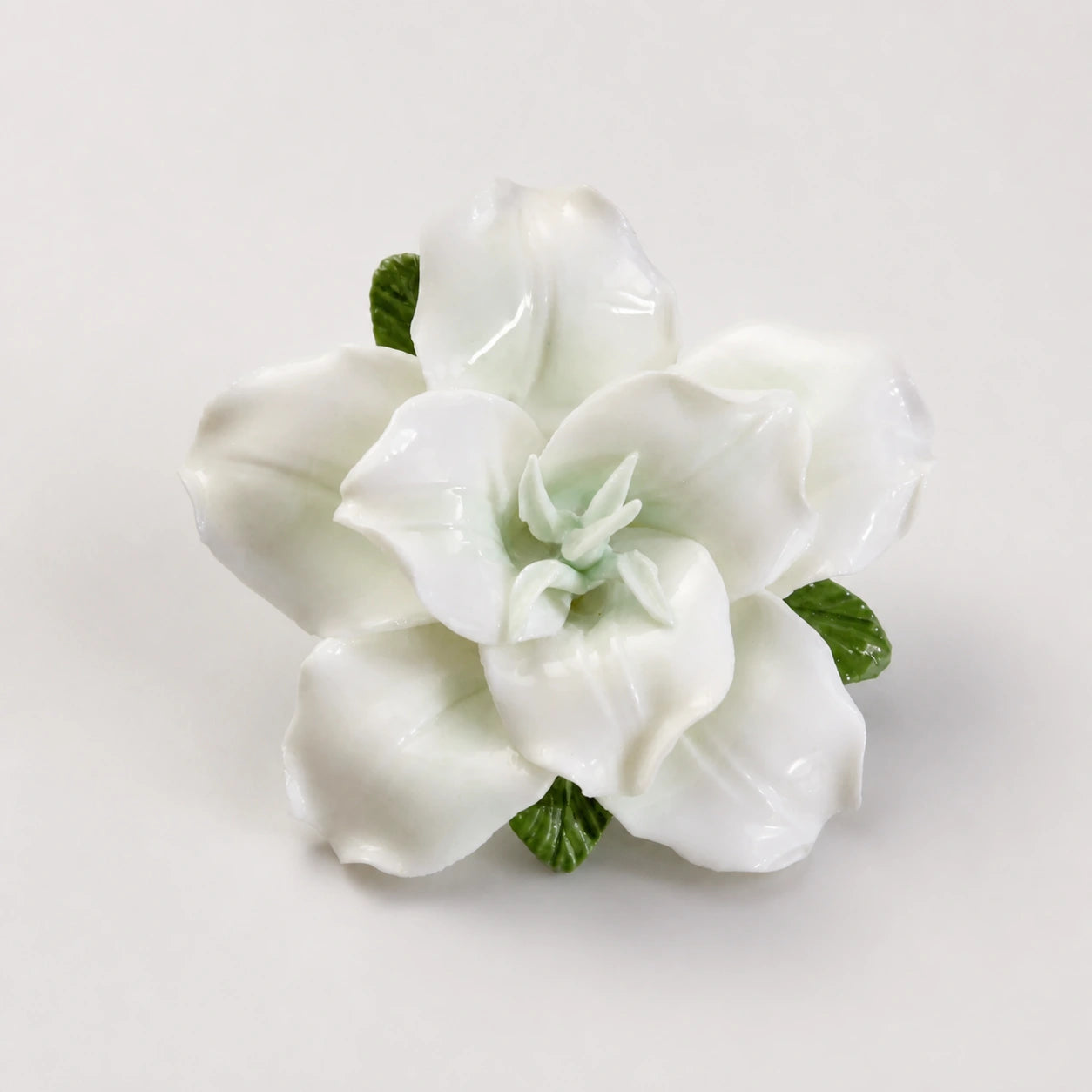 Pale green glazed ceramic lily refrigerator magnet on a light pearl-gray background.