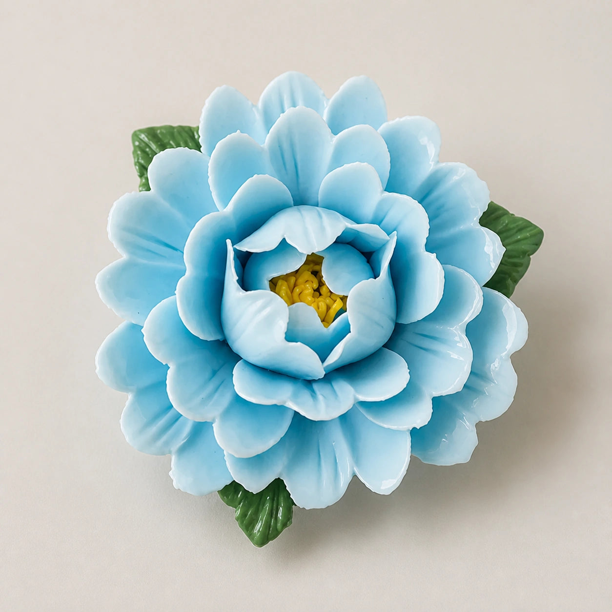 Aimant pivoine en céramique bleu poudré sur fond neutre clair.