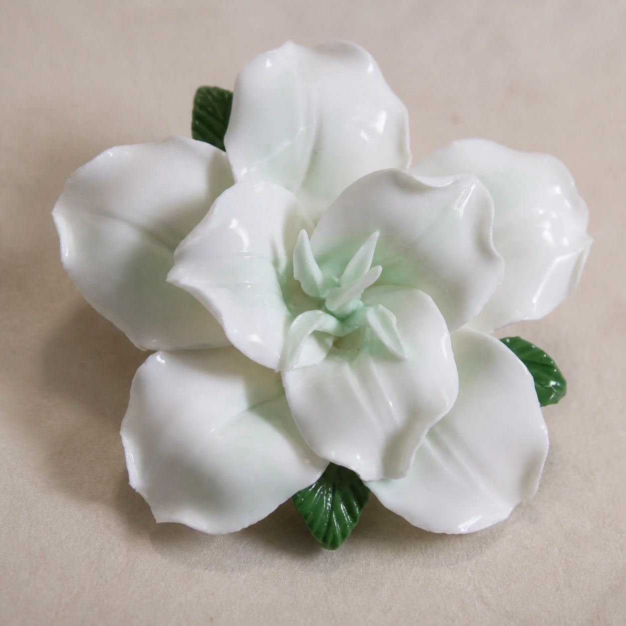 Close view of pale green glaze, pointed center petals and narrow ribbed leaf tips on a ceramic lily magnet.