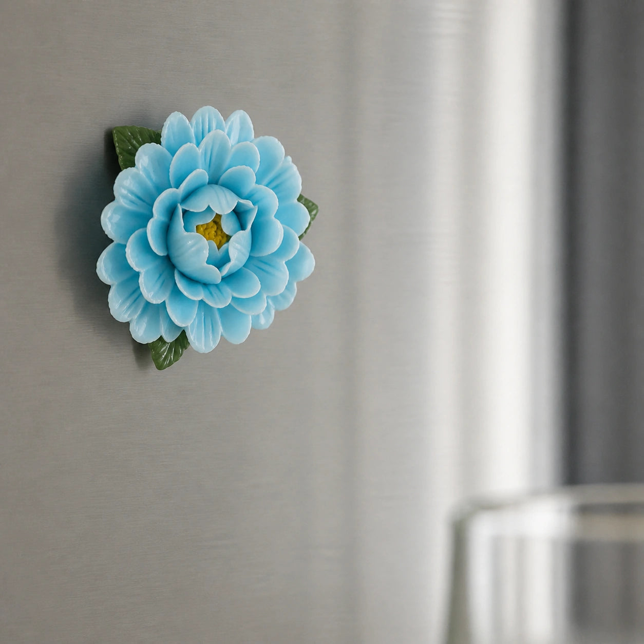 Aimant pivoine en céramique bleu poudré sur un réfrigérateur en acier inoxydable brossé.