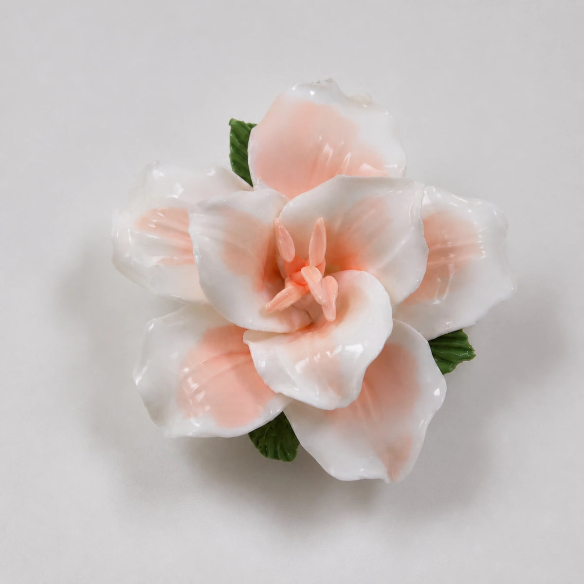 Soft orange glazed ceramic lily refrigerator magnet on a light pearl-gray background.