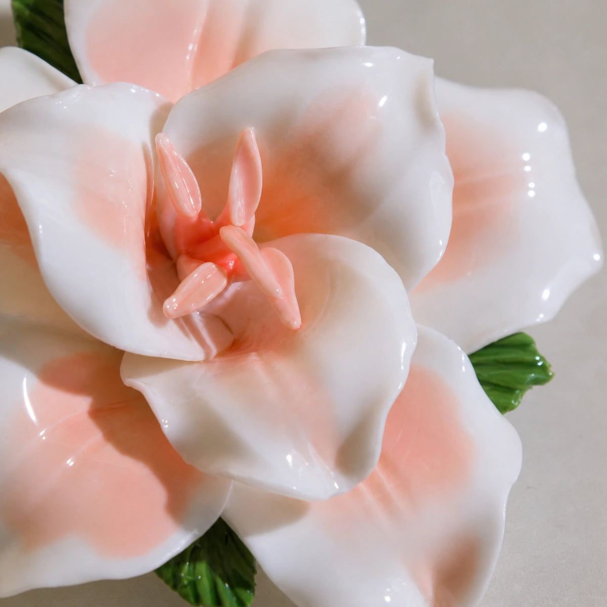 Close view of peach-orange glaze, curled white petals and the pointed center of a ceramic lily magnet.