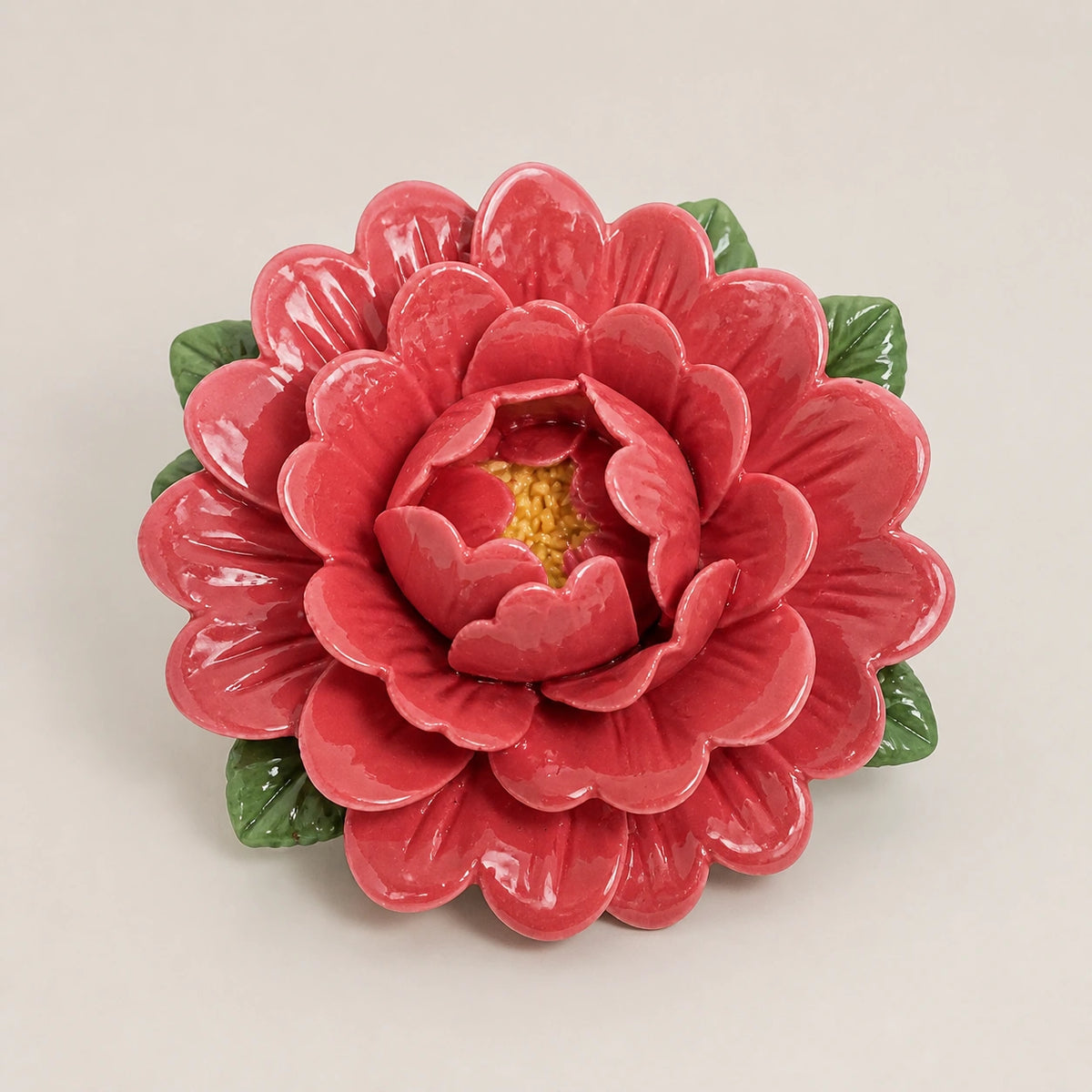 Aimant pivoine en céramique rouge rosé sur fond neutre clair.