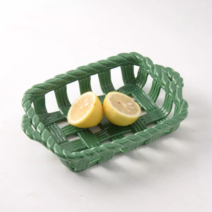 Glossy sage green rectangular woven ceramic tray holding two lemon halves against a white background.