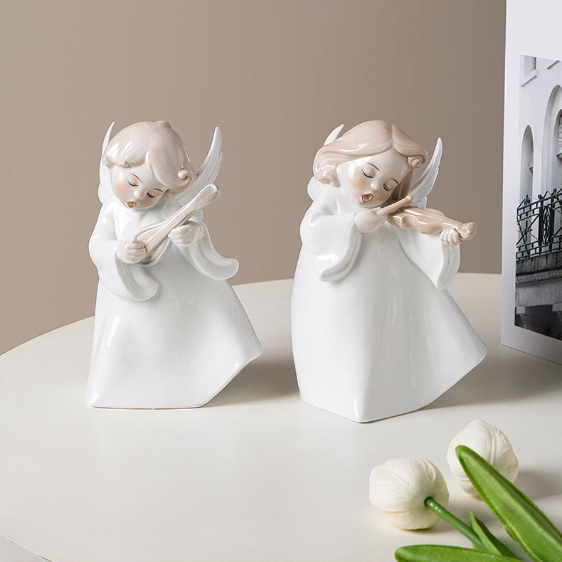 Two white angel figurines on a light surface with a neutral background