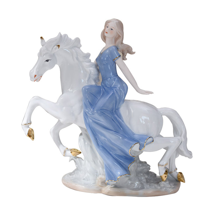 Porcelain figurine of a woman in a blue gown riding a rearing white horse with gold accents on a white background.