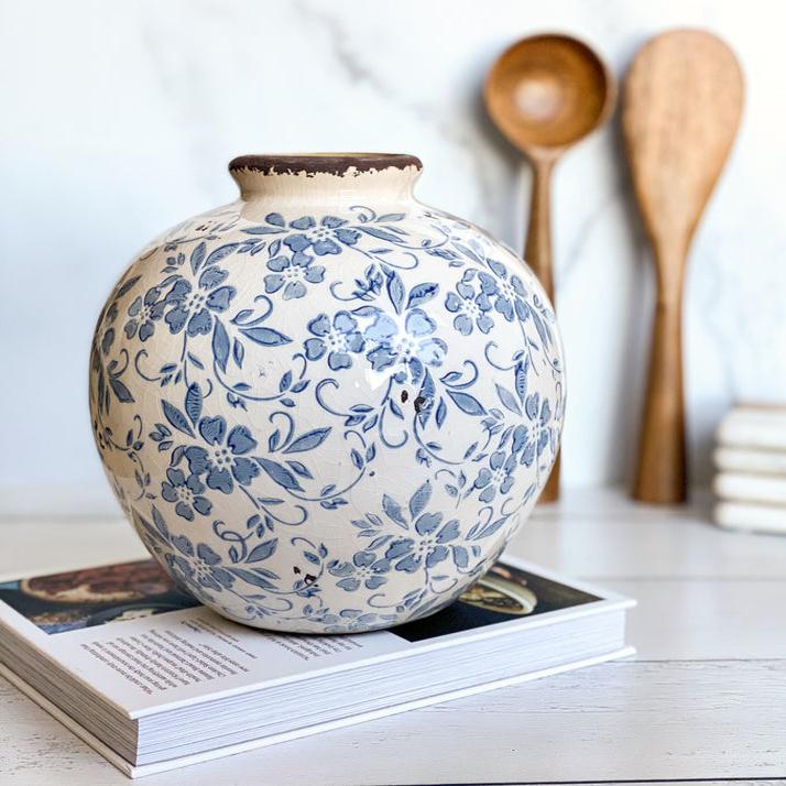 Ceramic vase with blue floral patterns on a white surface with wooden spoons in the background