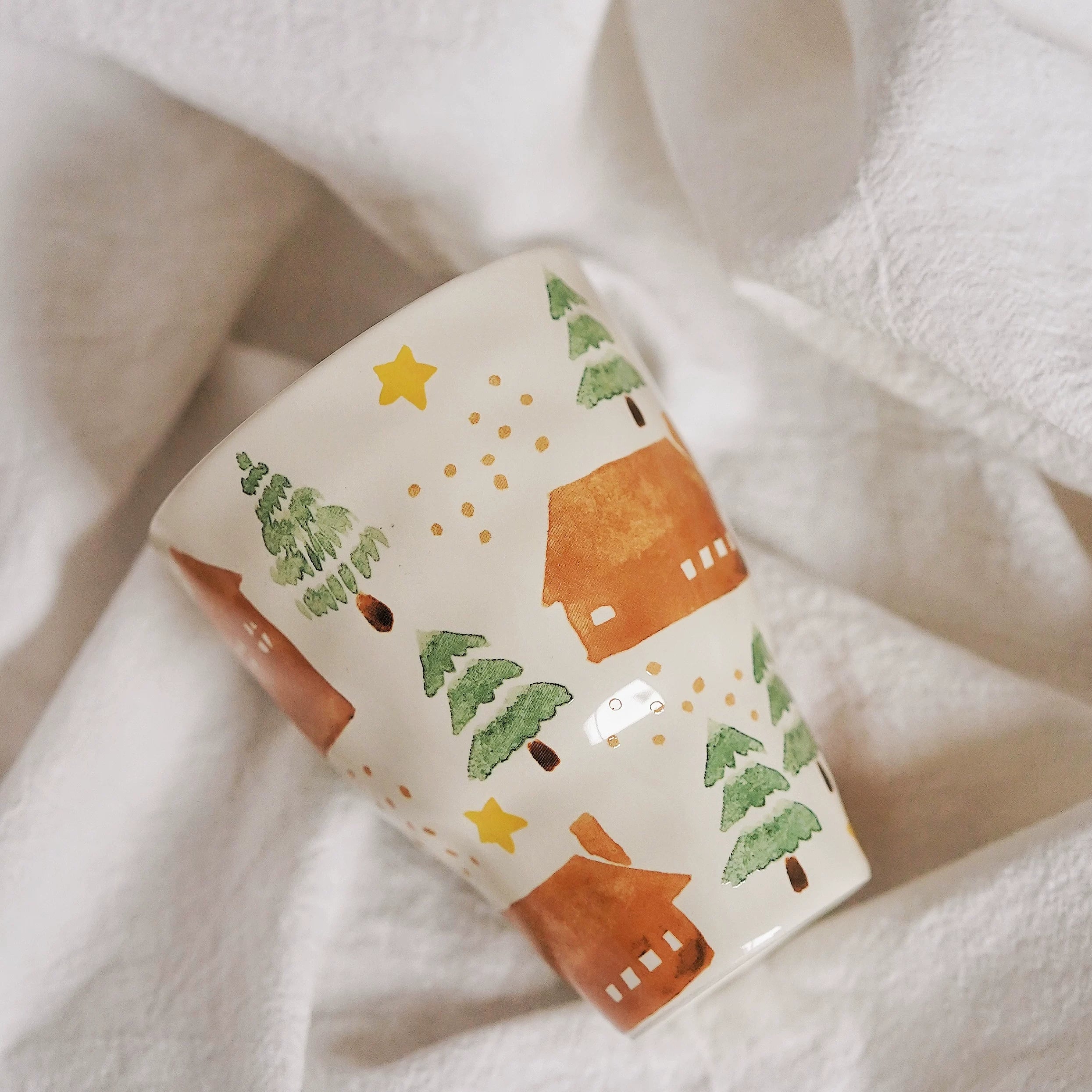 Close-up of pastoral ceramic mug with trees, houses and yellow star pattern