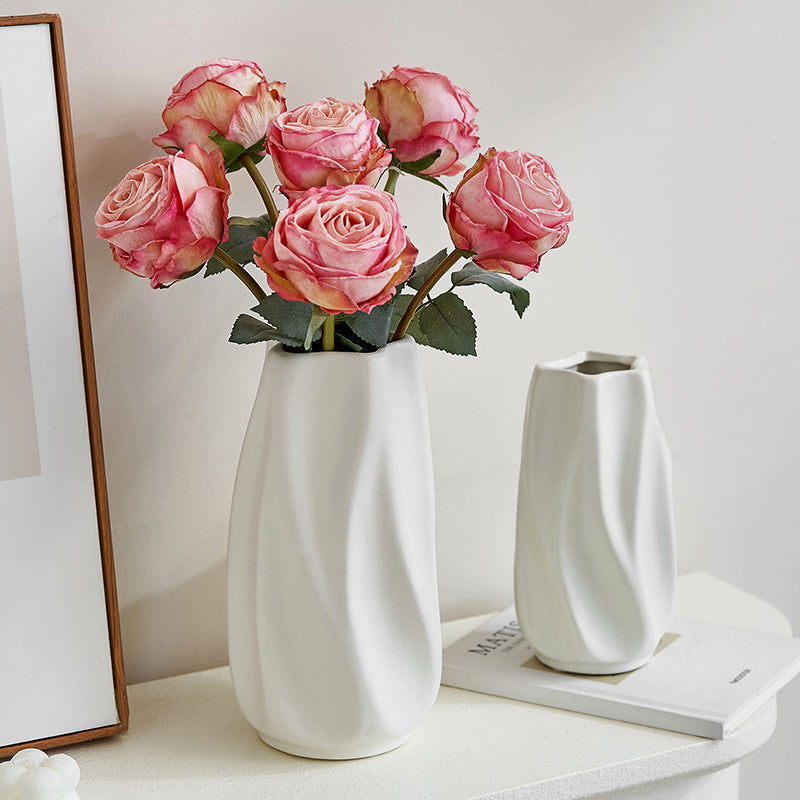 Modern white ceramic vases with pink roses on white table, minimalist home decor