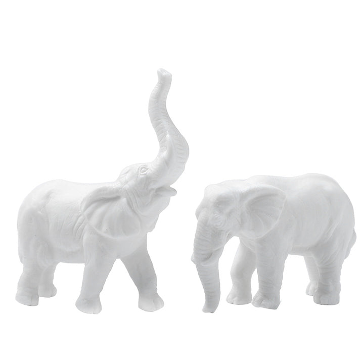 Two white elephant figurines, one with trunk raised and one with trunk lowered, on a white background