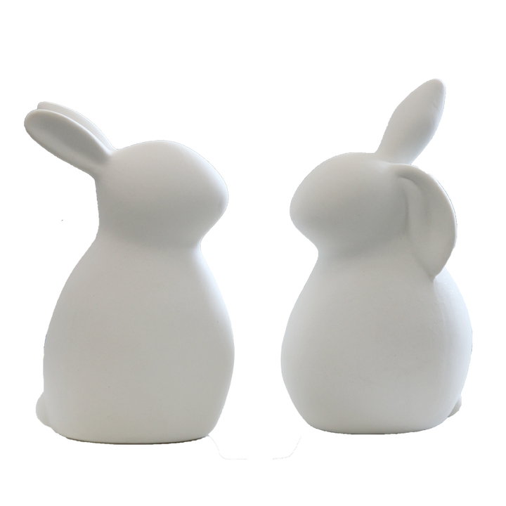 Two white ceramic rabbit figurines, one with swept-back ears and one with an upright and a drooping ear