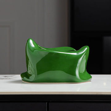 Green ceramic vase on a white surface with a dark background