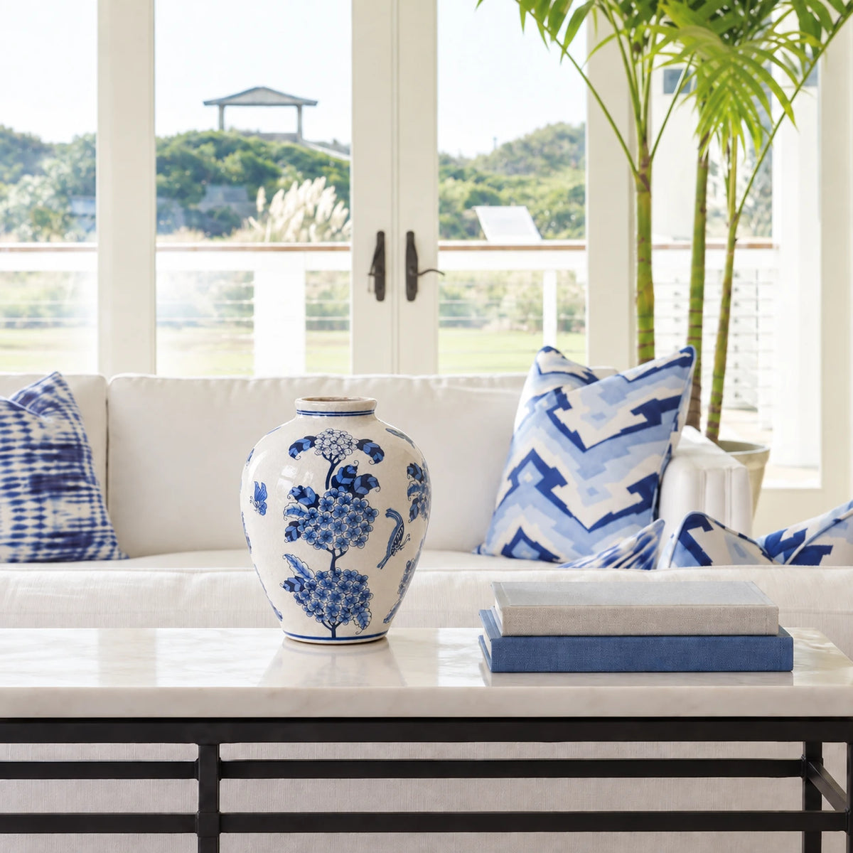 Large blue and white floral vase on a stone console beside blue and white sofa cushions.