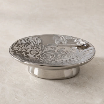 Baroque silver-tone ceramic soap dish with embossed floral relief on pale stone