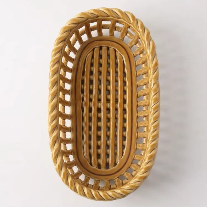 Overhead view of an empty glossy ochre oval ceramic basket showing parallel slatted base and twisted rim.