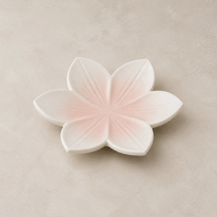 Blushing Sakura ceramic soap dish with six blush-pink petals on a warm neutral background
