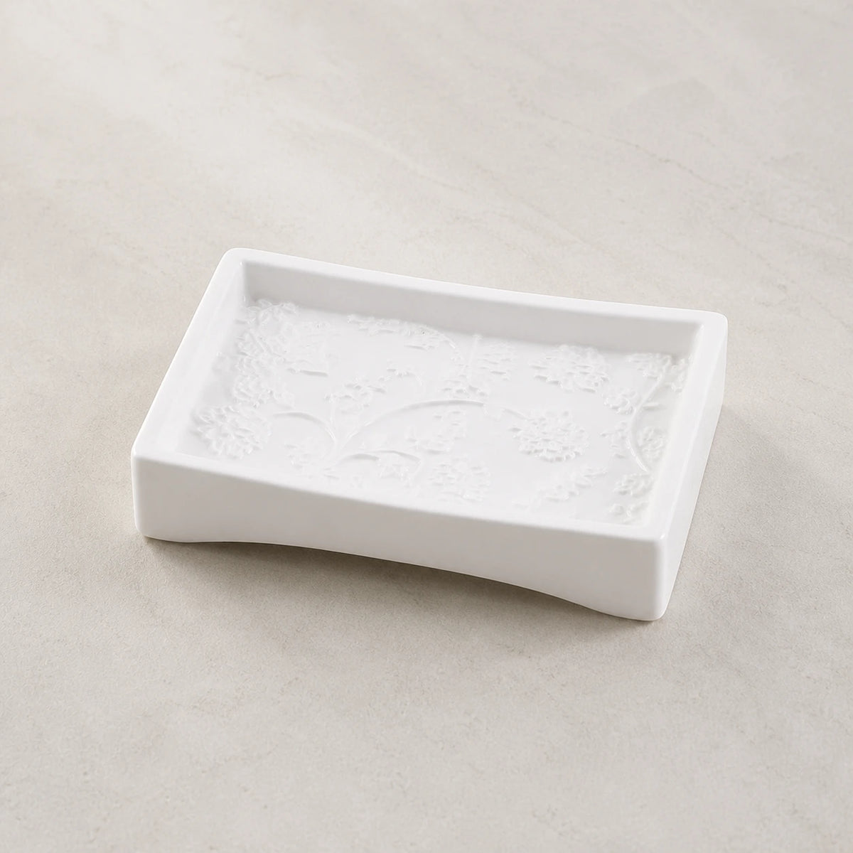 Detailansicht der weißen Keramik-Seifenschale mit erhabenem botanischem Relief und geschwungenem Rand
