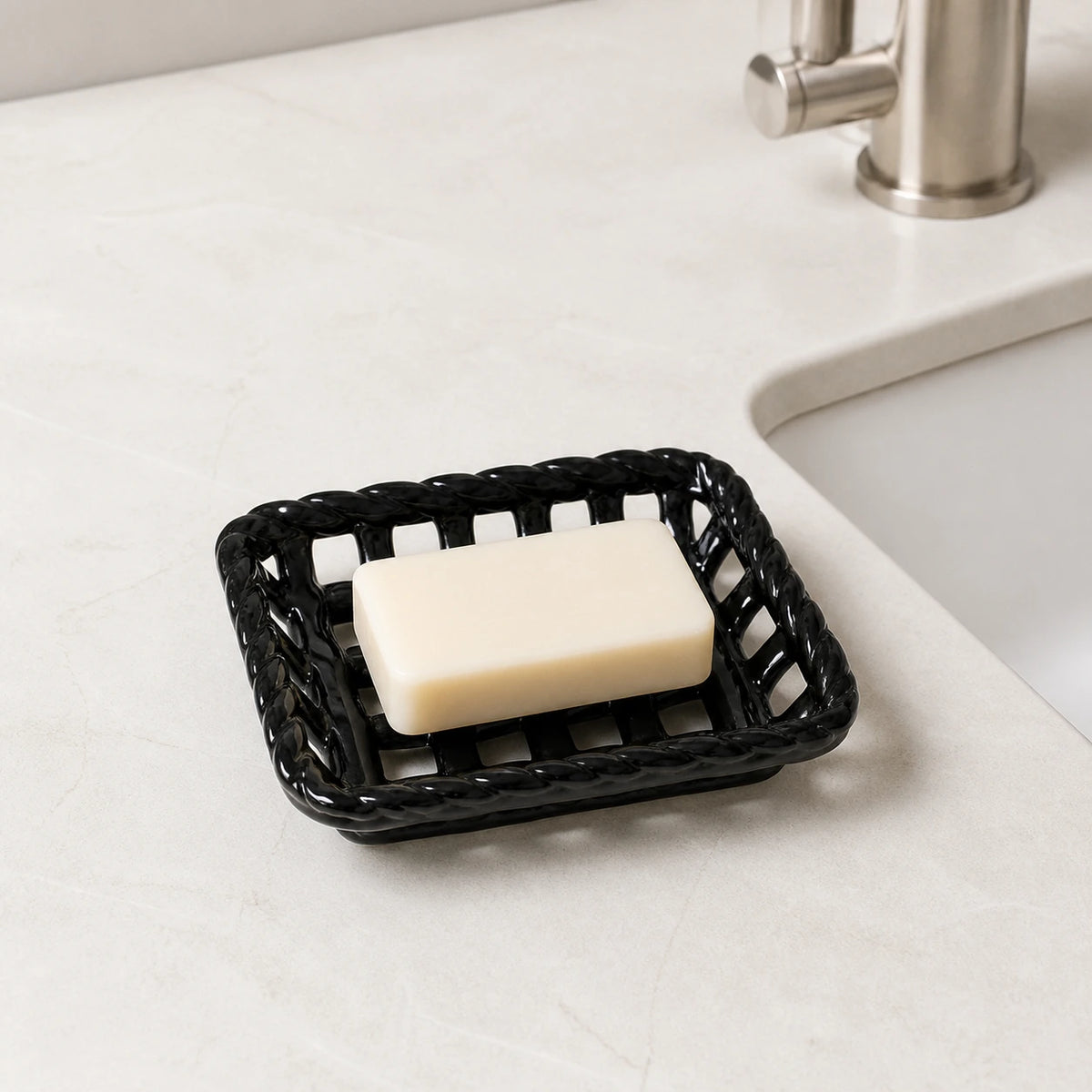 Glossy Noir ceramic soap basket holding an ivory bar beside a bathroom sink