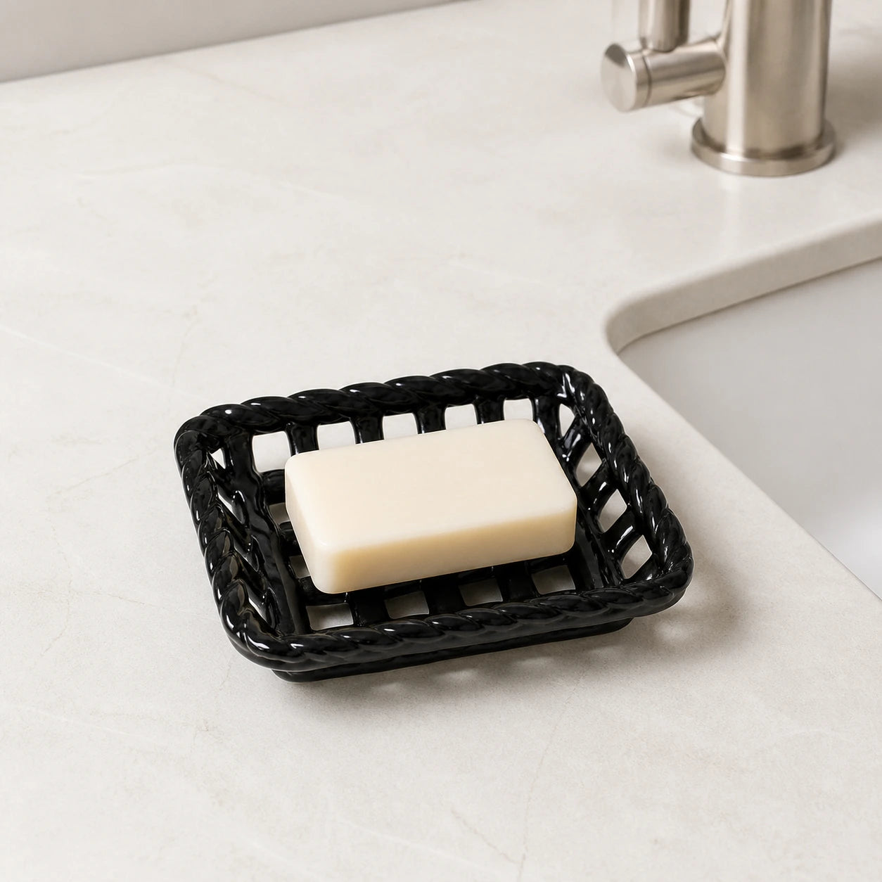 Glossy Noir ceramic soap basket holding an ivory bar beside a bathroom sink