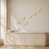 Multiple 12 cm Large Lotus Bloom ceramic wall flowers with golden yellow accent arranged as a wall grouping in a warm neutral interior.