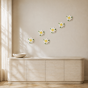 Multiple 12 cm Large Lotus Bloom ceramic wall flowers with golden yellow accent arranged as a wall grouping in a warm neutral interior.