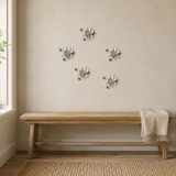 Multiple 12 cm Large Ruffled Peony ceramic wall flowers with plum purple accent arranged as a wall grouping in a warm neutral interior.