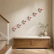 Multiple 12 cm Large Lotus Bloom ceramic wall flowers with rose red accent arranged as a wall grouping in a warm neutral interior.