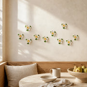 Multiple 7 cm Small Lotus Bloom ceramic wall flowers with golden yellow accent arranged as a wall grouping in a warm neutral interior.