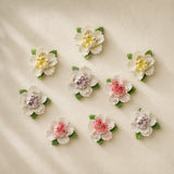 Small Ruffled Peony ceramic wall flowers with golden yellow, plum purple and rose red accents arranged together on a warm neutral wall.