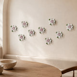 Multiple 9 cm Medium Lotus Bloom ceramic wall flowers with plum purple accent arranged as a wall grouping in a warm neutral interior.