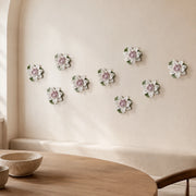 Multiple 9 cm Medium Lotus Bloom ceramic wall flowers with plum purple accent arranged as a wall grouping in a warm neutral interior.