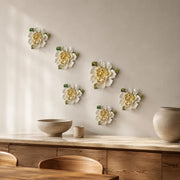 Multiple 12 cm Large Ruffled Peony ceramic wall flowers with golden yellow accent arranged as a wall grouping in a warm neutral interior.