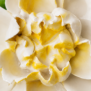 Close frontal view of the golden yellow center and layered glazed petals of the Medium Ruffled Peony ceramic wall flower.
