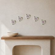 Multiple 12 cm Large Lotus Bloom ceramic wall flowers with plum purple accent arranged as a wall grouping in a warm neutral interior.