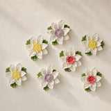Medium Lotus Bloom ceramic wall flowers with golden yellow, plum purple and rose red accents arranged together on a warm neutral wall.