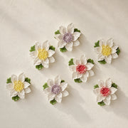 Medium Lotus Bloom ceramic wall flowers with golden yellow, plum purple and rose red accents arranged together on a warm neutral wall.