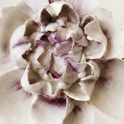 Close frontal view of the plum purple center and layered glazed petals of the Large Ruffled Peony ceramic wall flower.
