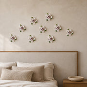 Multiple 7 cm Small Ruffled Peony ceramic wall flowers with plum purple accent arranged as a wall grouping in a warm neutral interior.