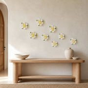 Multiple 9 cm Medium Ruffled Peony ceramic wall flowers with golden yellow accent arranged as a wall grouping in a warm neutral interior.