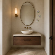 Multiple 7 cm Small Lotus Bloom ceramic wall flowers with plum purple accent arranged as a wall grouping in a warm neutral interior.