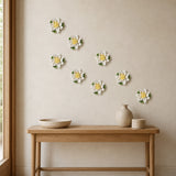 Multiple 9 cm Medium Lotus Bloom ceramic wall flowers with golden yellow accent arranged as a wall grouping in a warm neutral interior.