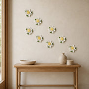Multiple 9 cm Medium Lotus Bloom ceramic wall flowers with golden yellow accent arranged as a wall grouping in a warm neutral interior.