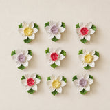 Small Lotus Bloom ceramic wall flowers with golden yellow, plum purple and rose red accents arranged together on a warm neutral wall.