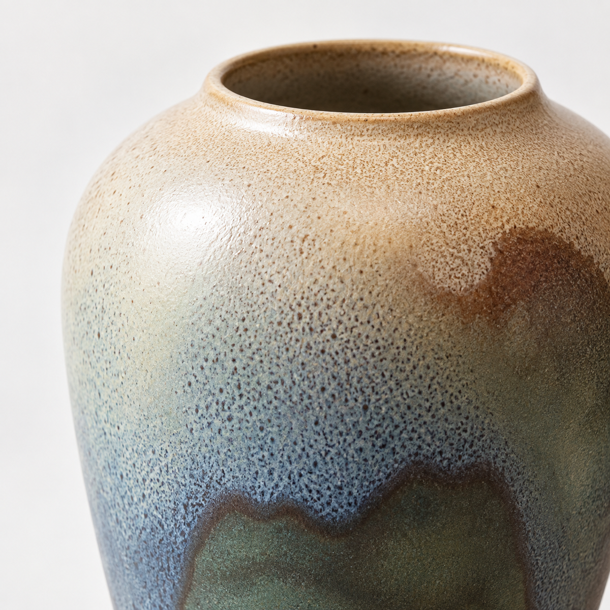 Medium blue-green reactive-glaze ceramic vase: layered blue-green glaze and its open rim.