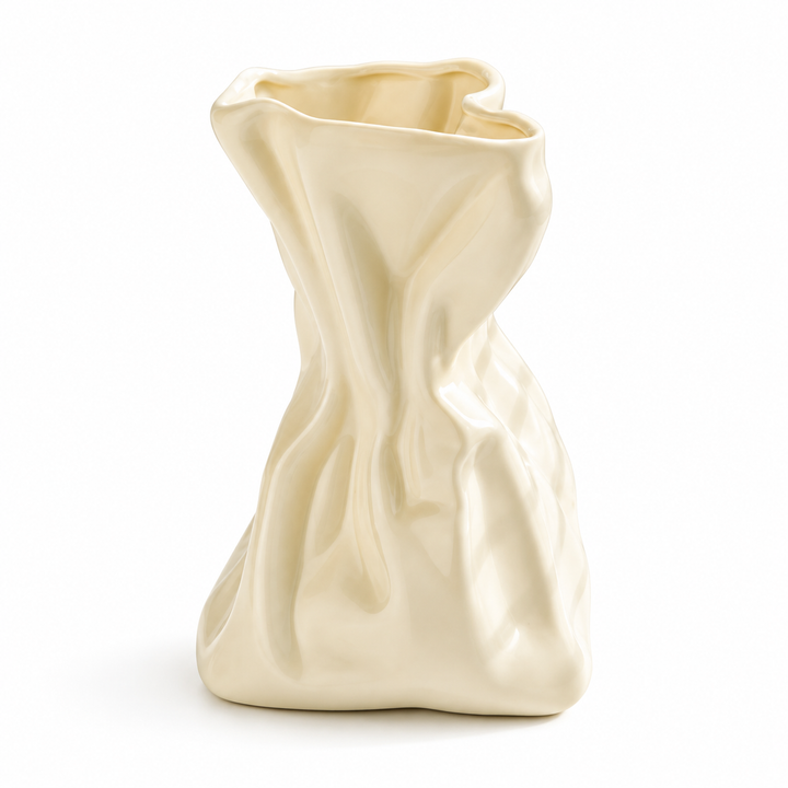 Elfenbeinfarbene Keramikvase in zerknitterter Papiertütenform vor weißem Studiohintergrund.